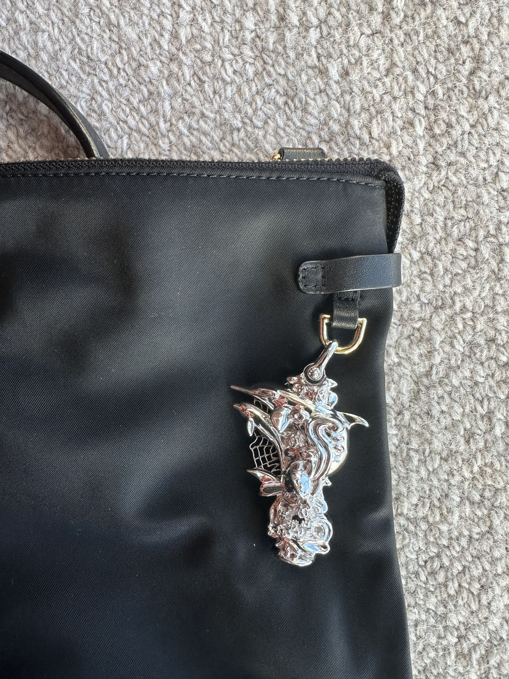 A sample pendant clipped by its D-ring onto a bag strap
